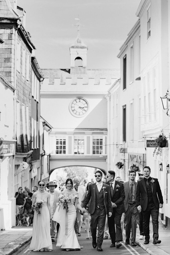 A wedding party walking through Totnes by Eastgate Clocktower