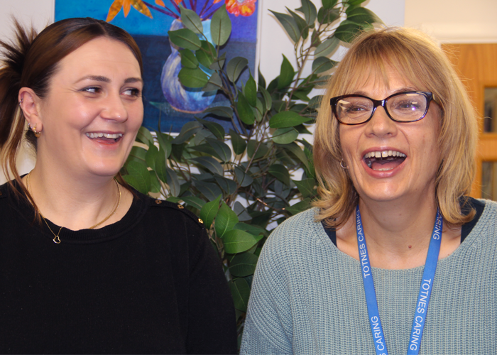 A blonde woman laughs while a brunette smiles at her.