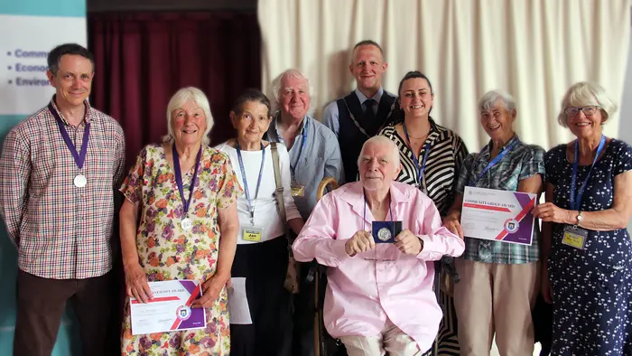 A group of older people holding awards and smiling to the camera.